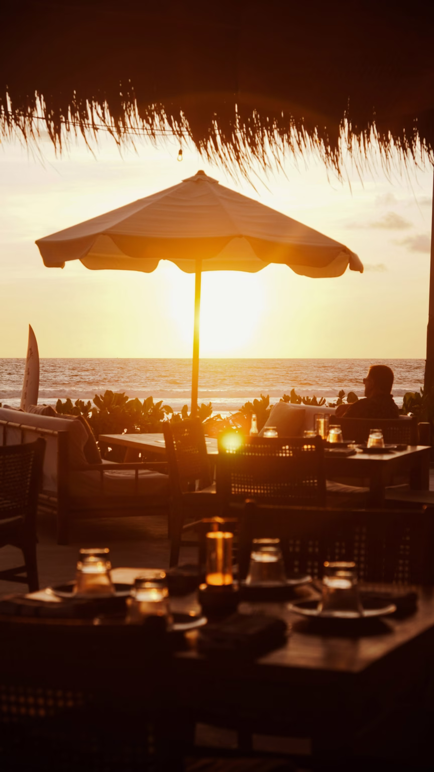 Tables under a parasol on the beach at sunset