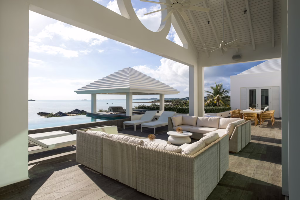 Covered terrace with white sofas facing the pool and sea